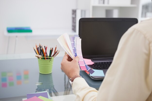 Ontwerper die bij zijn bureau met kleurensteekproef werkt