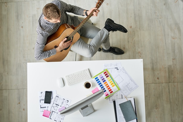 Ontwerper gitaar spelen op de werkplek