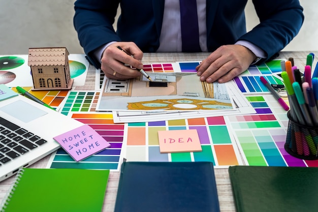 Ontwerper ontwikkelt een schets van interieurillustratie met kleurenschema van materiaal op een tafel, kantoorwerkplek. Desktop van een architect en interieurontwerper met voorbeelden van apparatuur en materialen