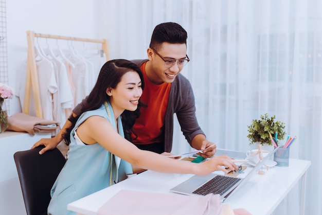 Ontwerpersteam bespreken modeschetsen, gerichte man en vrouw die samenwerken aan het maken van nieuwe kledingcollecties, kleur kiezen werken met stalen pantone op de werkplek