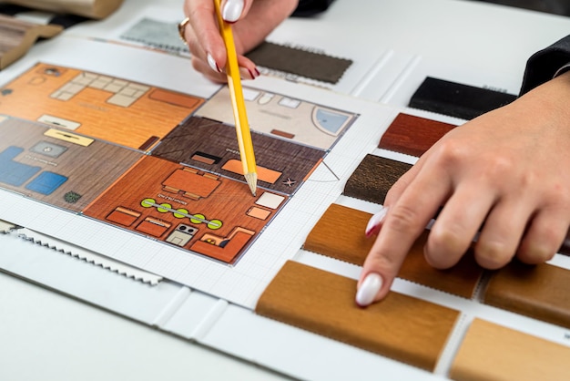 Ontwerpervrouw plant interieur, illustreert en kiest perfecte kleuren voor een nieuw huis met voorbeelden van houtmaterialen op tafel Zakelijke ideeën voor het ontwerp van onroerend goed