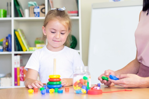 Ontwikkelings- en logopedische lessen met een kind-meisje. Logopedie-oefeningen en spelletjes met een gekleurde piramide