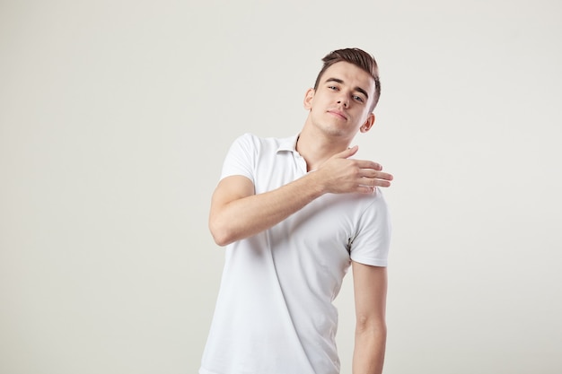 Onverschillige man gekleed in een wit t-shirt en jeans is op een witte achtergrond in de studio.