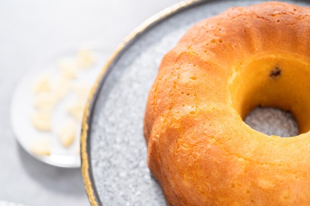 Onversierde citroen cranberry bundt cake op een taartplateau.