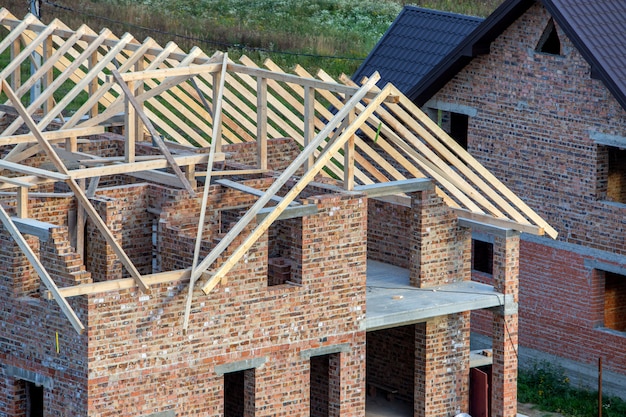 Onvoltooide bakstenen huis met houten dakconstructie in aanbouw.