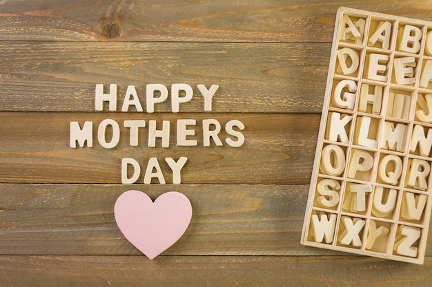 Onvoltooide houten letters ondertekenen Happy Mother's Day op een geschilderde houten achtergrond.