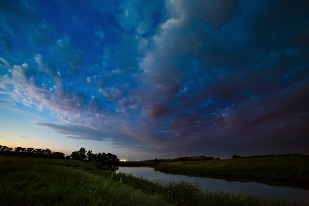 Onweerswolken aan de hemel na zonsondergang op de rivier