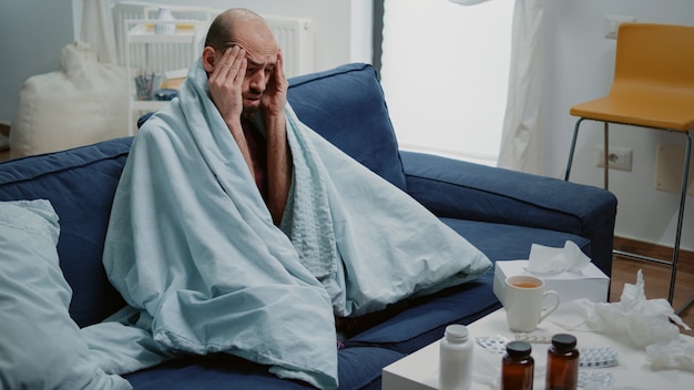 Onwel man met hoofdpijn die over de slapen wrijft en zich ziek voelt