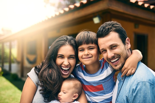 Onze grote gelukkige familie Bijgesneden portret van een gelukkig jong gezin van vier buiten met hun huis op de achtergrond