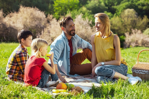 Onze vakanties. aantrekkelijke gelukkige moeder die en picknick met haar familie glimlacht heeft