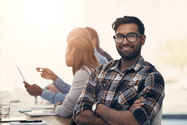 Onze vergaderingen staan in het teken van vooruitgang Portret van een zelfverzekerde jonge zakenman die een vergadering bijwoont met collega's in een modern kantoor