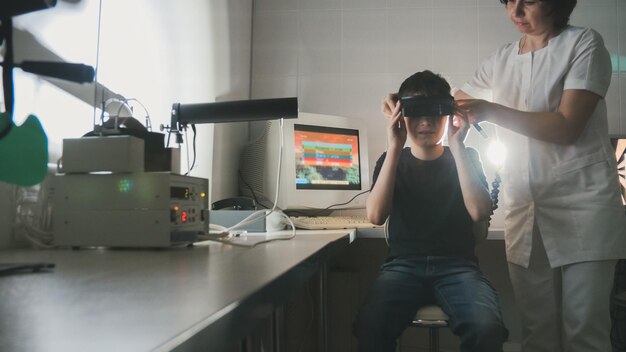 Oogarts controleert het zicht van de jongen met behulp van een stereovideo virtual reality-bril, groothoek