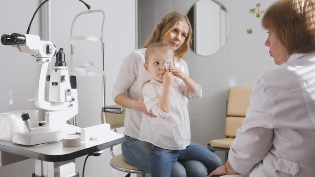 Oogarts in kliniek legt diagnose uit over het gezichtsvermogen van meisjes - kinderspelletjes, horizontaal