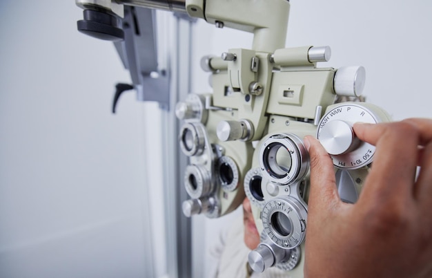 Oogonderzoek visie en handen van optometrist met patiënt in kliniek voor test gezichtsvermogen en optische beoordeling Optometrie gezondheidszorg en opticien met vrouw in phoropter medische machine en lens