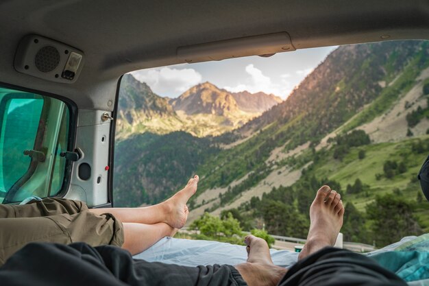 Oogpunt van de benen van een romantisch stel in een oud busje dat samen geniet van het geweldige landschap