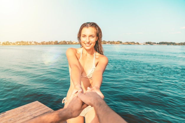 Oogpunt van een jonge vrouw in een badpak die plezier heeft met haar partner aan zee