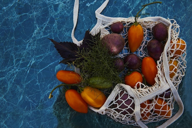 Oogst groenten in eco boodschappentas met kleurrijke tomaten aubergines paarse aardappelen onder trendy harde schaduwen met reflectie achtergrond Ecologische zorg Ruimte kopiëren