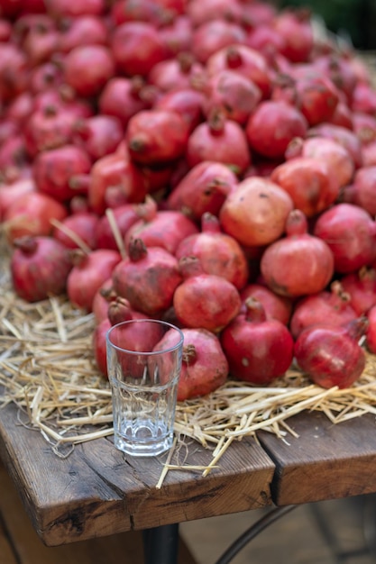 Oogst van rijpe granaatappels voor sap met glas en flessen op houten tafel op boerenmarkt