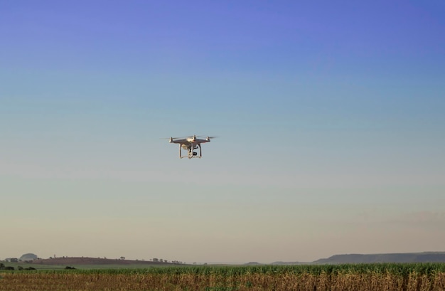 Oogstmachine die werkt aan een suikerrietveldplantage-drone die wordt bewaakt op een kleurrijke hemelachtergrond