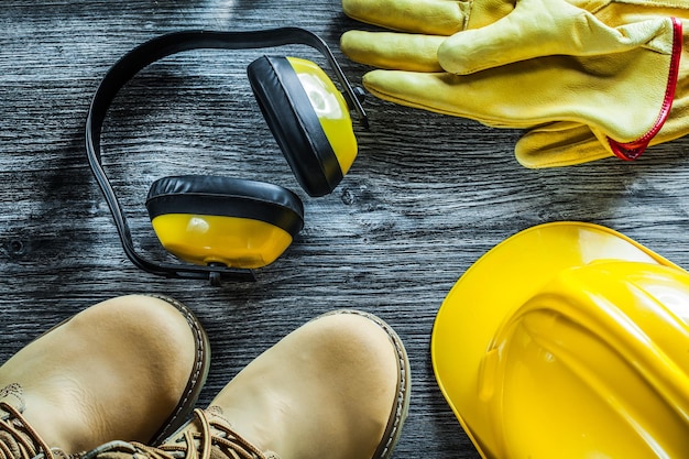 Foto oorbeschermers beschermende handschoenen veiligheidskap laarzen op houten plank