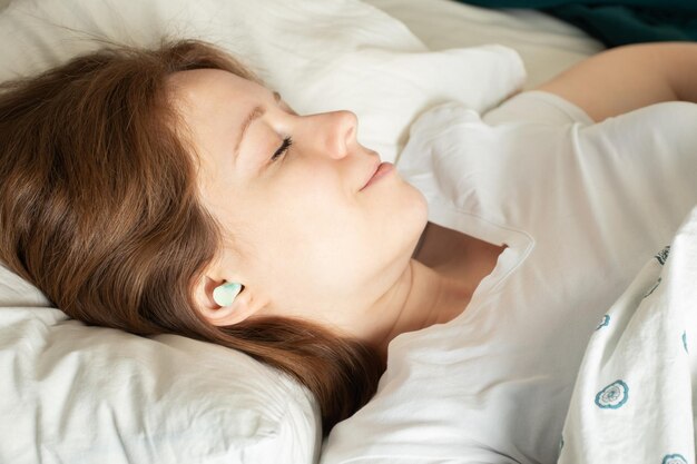 Oordopjesvrouw die goed slaapt in bed met oordopjes.