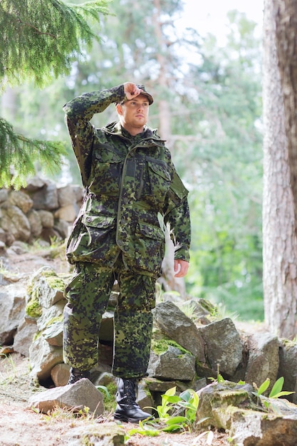 oorlog, leger en mensen concept - jonge soldaat of boswachter die militair uniform draagt in het bos