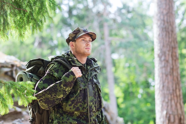 Foto oorlog, wandelen, leger en mensen concept - jonge soldaat of ranger met rugzak wandelen in het bos