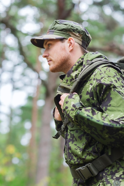 oorlog, wandelen, leger en mensen concept - jonge soldaat of ranger met rugzak wandelen in het bos