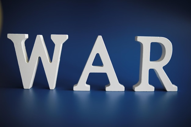 Oorlog woord geschreven in houten alfabet letters op blauwe achtergrond het concept van een verschrikkelijke oorlog die land vernietigt