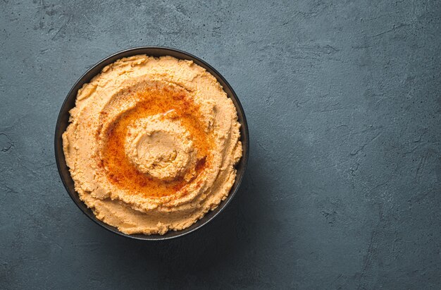 Oosterse hummus met paprika en olijfolie op een donkere achtergrond