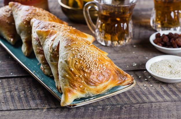 Oosterse keuken. heerlijke samosas samsa met vlees, glas thee op houten tafel. ramadan eten