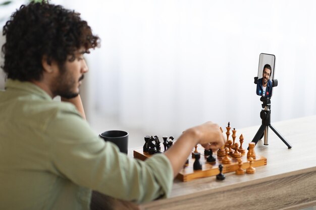 Oosterse man aan het schaken met zijn vriend via videogesprek