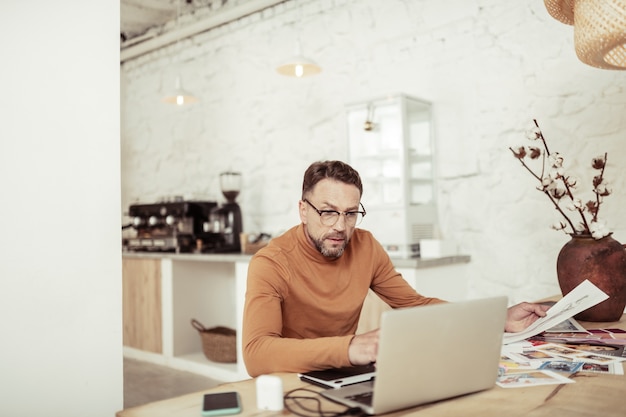 Op afstand werken. gerichte modeontwerper die thuis naar zijn laptop op tafel kijkt.