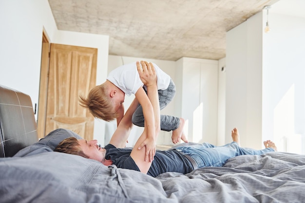 Op bed liggen Vader en zoon zijn samen binnen thuis