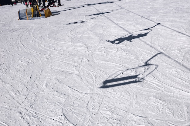 Op de berghelling worden de schaduwen weergegeven van de skiërs die de skilift opgaan