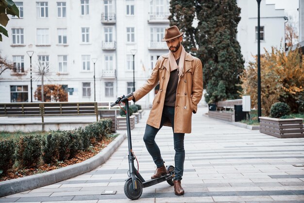 Op de elektrische scooter is een jong mannelijk model in modieuze kleding overdag buiten in de stad
