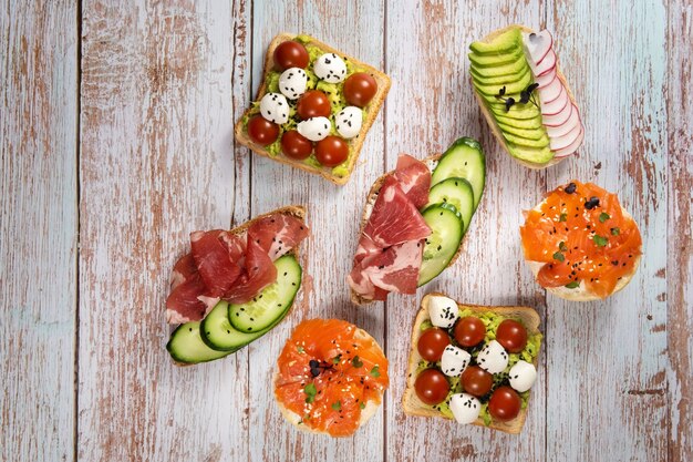 Foto op de houten tafel lag een assortiment sandwiches met vis, kaas, vlees en groenten.