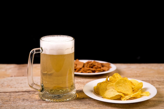 Op de houten tafel staat een mok waar bier in zit.