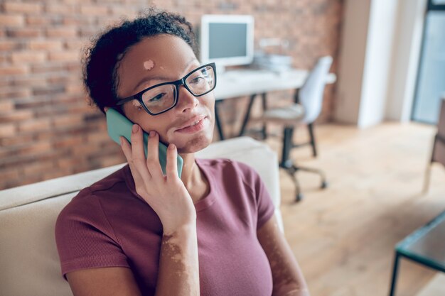 Op de oproep. Een vrouw met een bril die aan de telefoon praat en er betrokken uitziet