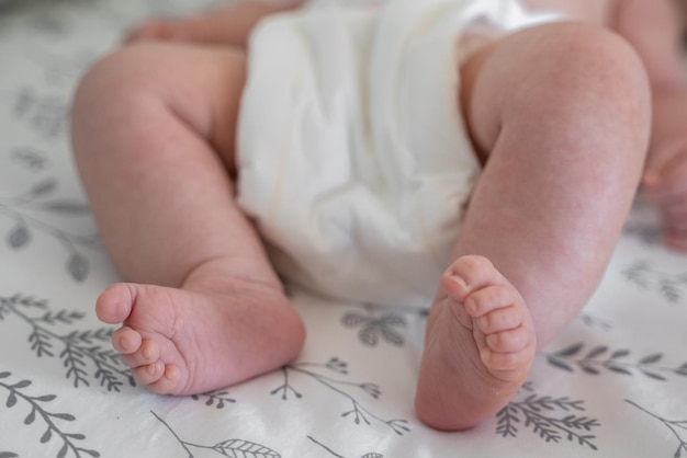 Op de sprei liggen kleine kindervoeten. Leuk pasgeboren concept