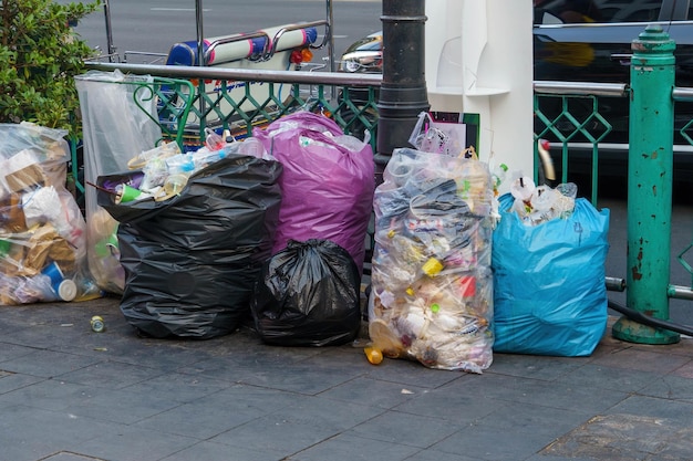 Foto op de stoep staat een groepje vuilniszakken opgesteld.