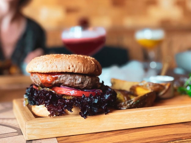 Op de tafel van het restaurant een burger met een kalfskotelet een ring van rode ui basilicum een tomaat en