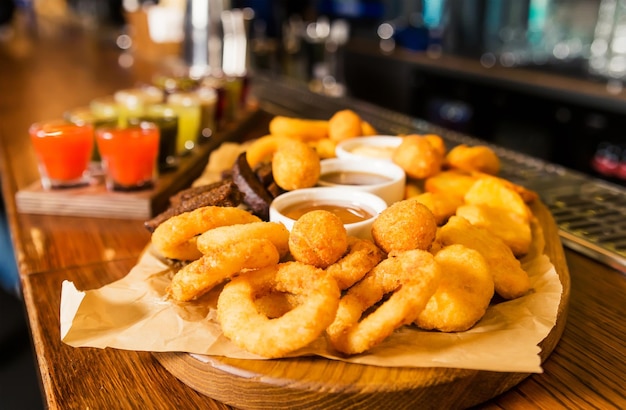 Op de toog staat een set van diverse tincturen en een bord met hapjes uienringen kaasstengels balletjes en croutons