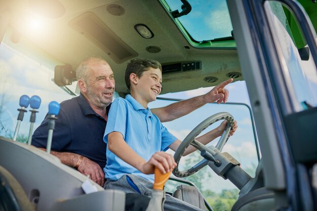 Op die manier Bijgesneden opname van een mannelijke boer en zijn zoon in de cockpit van een moderne tractor