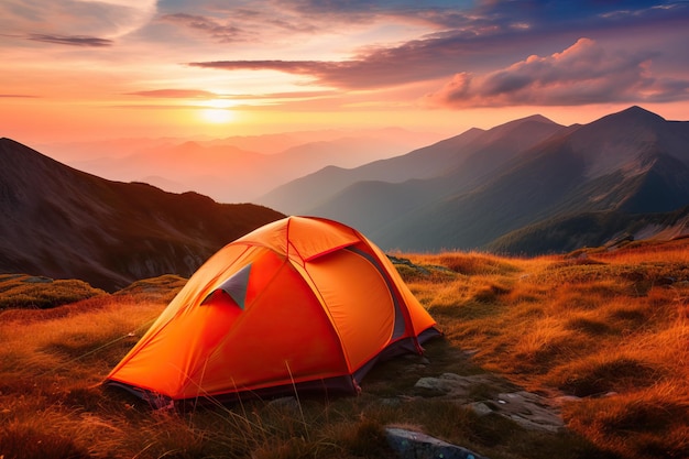 Op een berg is een tent opgezet met daarachter de ondergaande zon.