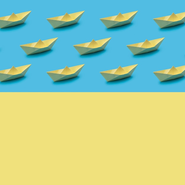 Op een blauwe achtergrond een patroon van gele papieren boten origami close-up behang en gele backgr