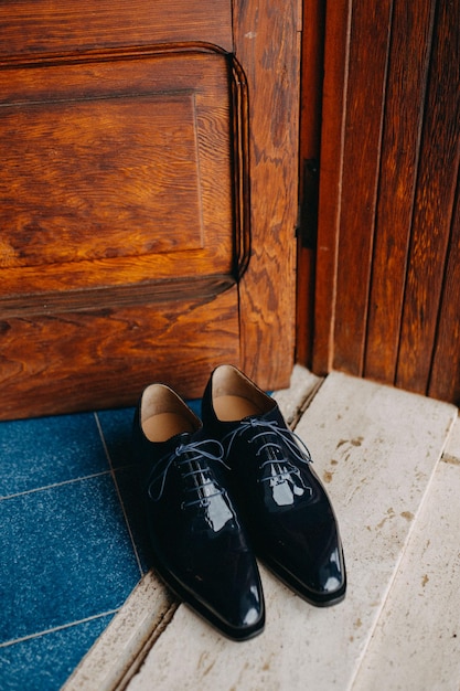 Foto op een blauwe tegelvloer staan een paar zwarte schoenen.