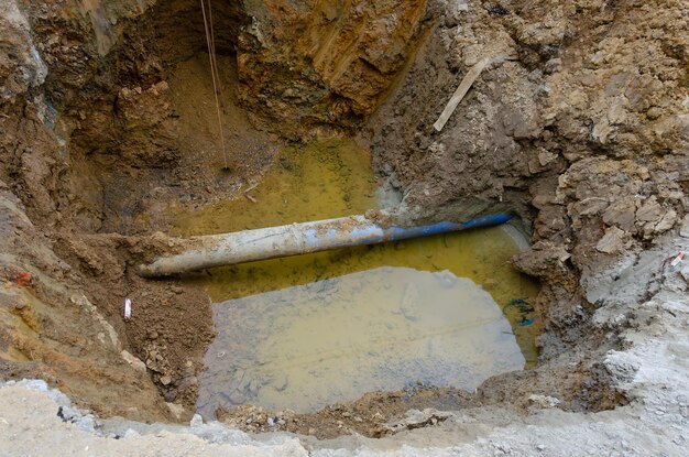 Op een bouwplaats wordt een waterleiding gegraven in een gat.