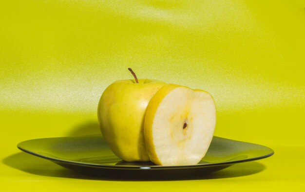 Op een groene achtergrond met gele appels op een bord.
