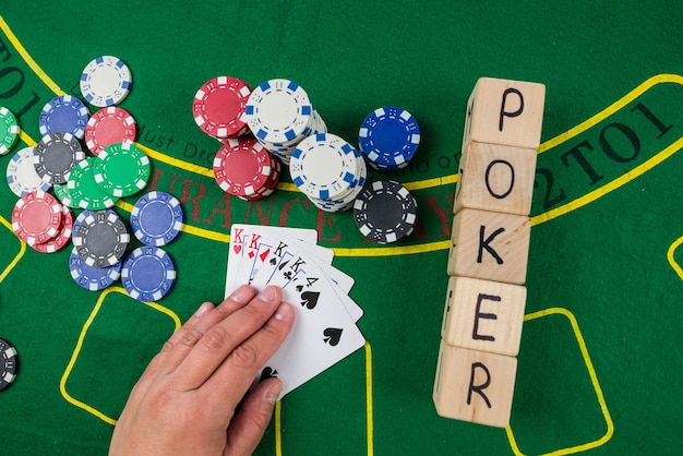 Op een groene pokertafel zijn kaartenchips en de inscriptie poker op houten kubussen Pokerconcept